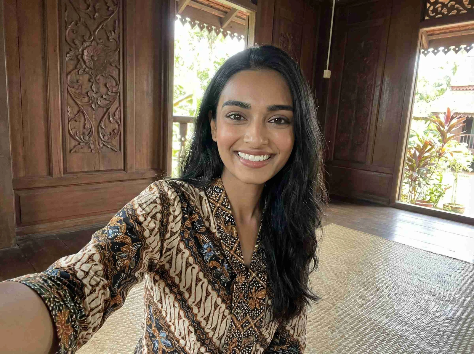 A smiling woman framed by carved wooden architecture